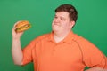 Portrait of a fat guy with a big hamburger in his hands, isolated on a green background. Chroma key, green screen