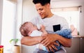 A portrait of father bottle feeding a small toddler son indoors at home.