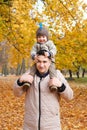 Portrait of a father carrying his cute little son on shoulders, baby and daddy with pleasure spending time together Royalty Free Stock Photo