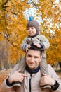 Portrait of a father carrying his cute little son on shoulders, baby and daddy with pleasure spending time together Royalty Free Stock Photo