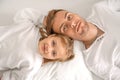 Portrait of a father and cute carefree child lying on a bed, top view