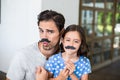 Portrait of father and daughter with artificial mustache