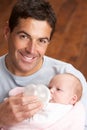 Portrait Of Father Feeding Newborn Baby At Home