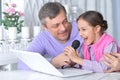 Portrait of father with little daughter singing karaoke