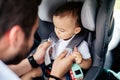 Portrait of young father securing baby in child seat of car Royalty Free Stock Photo