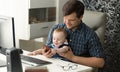 Portrait of father working at computer playing with his baby son Royalty Free Stock Photo