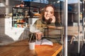 Portrait of a fatty smiling woman sitting in a cafe and calling at the cellphone. View through the cafe window, double