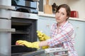 Portrait Of Fed Up Woman Cleaning Oven Royalty Free Stock Photo