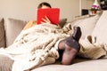 A portrait of the feet of a woman in black nylon stockings or pantyhose with reinforced toes lying in a couch under a cosy blanket Royalty Free Stock Photo