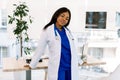 Portrait of a female African doctor in medical uniform posing in bright modern hospital Royalty Free Stock Photo