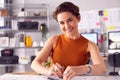 Portrait Of Female Architect At Desk In Office Measuring Plan Or Blueprint With Ruler