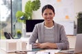 Portrait Of Female Architect In Office Sitting At Desk With Model Of New Building Royalty Free Stock Photo