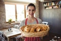 Portrait Of Female Baker Holding A Basket Of Bread Loafs