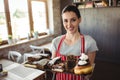 Portrait of female baker holding a tray of sweet foods