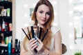 Portrait of female beautician holding a set of makeup brushes in beauty salon