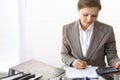 Portrait of female bookkeeper or financial inspector making report, calculating or checking balance. Copy space area