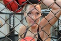 Portrait female boxer looking through metal fencing