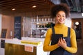 Portrait Of Female Business Owner Of Coffee Shop In Mask Using Digital Tablet During Health Pandemic