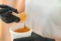 Portrait of a female caucasian beautician holding a jar of sugar paste for sugaring