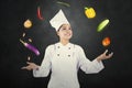 Female chef juggles food ingredients in dark room Royalty Free Stock Photo