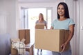 Portrait Of Female Couple Carrying Boxes Through Front Door Of New Home On Moving Day Royalty Free Stock Photo