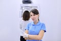 Portrait of female dental clinic worker, diagnostic dental x-ray equipment background