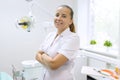 Portrait of female dentist with crossed arms, doctor smiling on dental chair background. Medicine, dentistry and healthcare concep