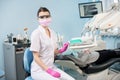 Portrait of female dentist with patient in the dental clinic. Doctor wearing glasses, mask, uniform and pink gloves Royalty Free Stock Photo