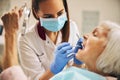 Portrait of female dentist who treating teeth of elderly woman patient Royalty Free Stock Photo