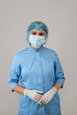 Portrait female doctor in blue uniform with protective medical gloves, mask cap isolated on grey Royalty Free Stock Photo