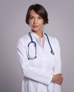 Smiling female doctor with stethoscope standing at isolated background Royalty Free Stock Photo