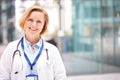 Portrait Of Female Doctor With Stethoscope Wearing White Coat Standing In Modern Hospital Building