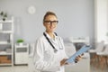 Portrait of female doctor, therapist, general practitioner, standing in hospital with clipboard. Royalty Free Stock Photo