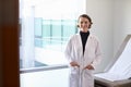 Portrait Of Female Doctor Wearing White Coat In Exam Room