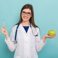 Female doctor in glasses with apple and pills Royalty Free Stock Photo