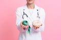 Portrait of female doctor with stethoscope holding measuring tape and donut isolated. Royalty Free Stock Photo