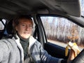 Portrait of female driver in solo journey. Adult mature middle aged woman holding steering wheel and banana. Eating