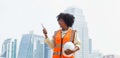 Portrait of a female engineer at a construction site. The construction manager stood in an orange life jacket and a white hard hat