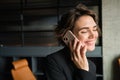 Portrait of female entrepreneur having a conversation over the phone, answers a call on her smartphone, standing in Royalty Free Stock Photo