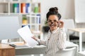 Portrait of female entrepreneur working with documents at desk in office, taking off glasses and smiling at camera Royalty Free Stock Photo