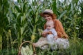 Portrait of female farmer with beautiful baby harvesting corn on the field. Royalty Free Stock Photo