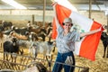 Portrait of female farmer with Peruvian flag in their hands in goat pen at farm Royalty Free Stock Photo