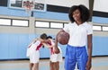 Portrait Of Female High School Basketball Coach With Team Huddle In Background Royalty Free Stock Photo