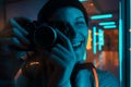 Smiling female photographer using camera in neon light