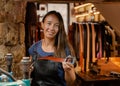 Portrait of a female leather artisan in her workshop with hand-made belt