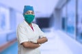 Portrait Of Female Medical Worker Doctor Wearing Surgical Mask And Cap Standing Crossed Arms Outside Hospital Corridor. Covid-19, Royalty Free Stock Photo