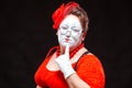 Portrait of female mime artist, isolated on black background. Racy woman touches her chin with a finger looking languid