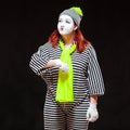 Portrait of female mime artist, isolated on black background. Young woman in striped clothes and bright yellow scarf is Royalty Free Stock Photo