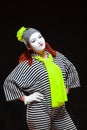 Portrait of female mime artist, isolated on black background. Young woman in striped clothes and bright yellow scarf is Royalty Free Stock Photo