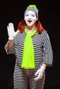 Portrait of female mime artist, isolated on black background. Young woman in striped clothes and bright yellow scarf Royalty Free Stock Photo